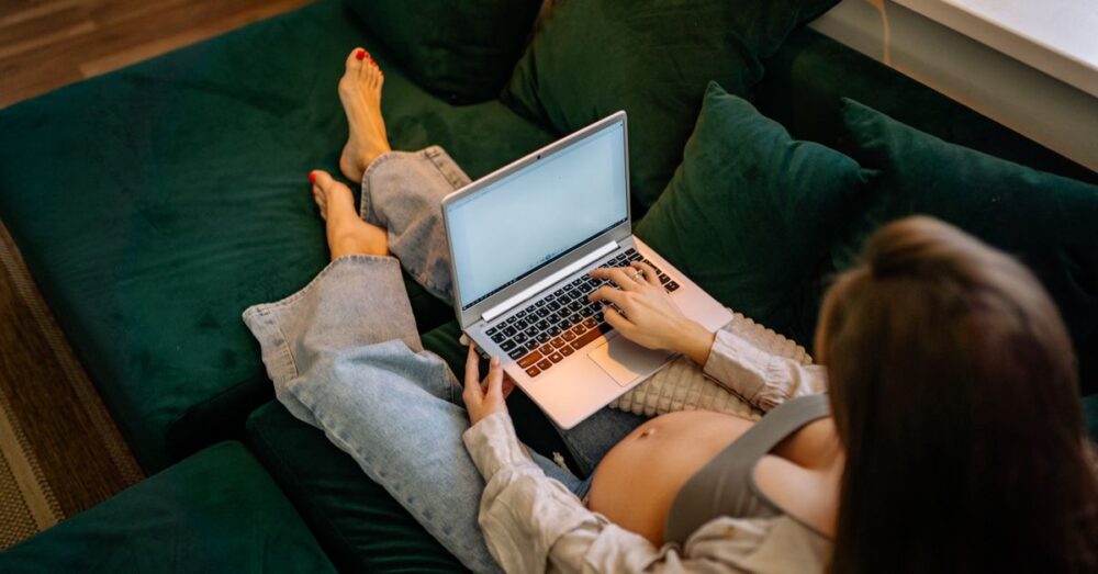 ノートパソコンで作業する妊娠中の女性